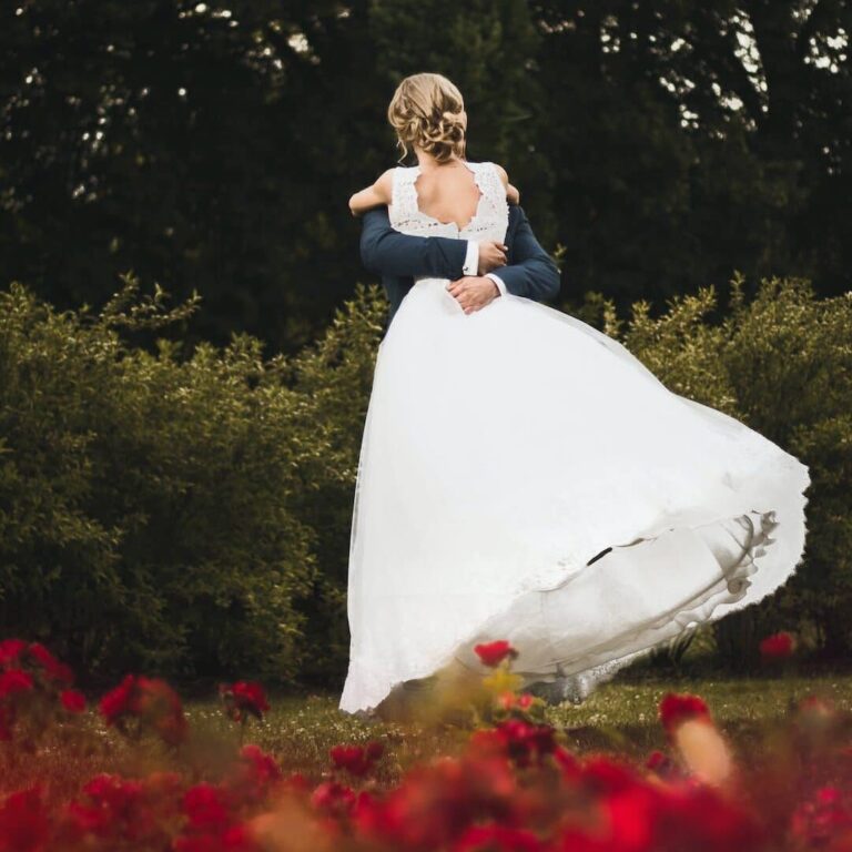 mariée en robe blanche devant des roses rouges